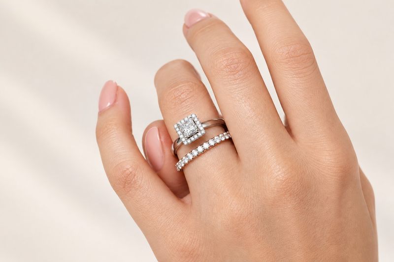 bague de fiançailles à halo carré portée avec une alliance sertie de diamants